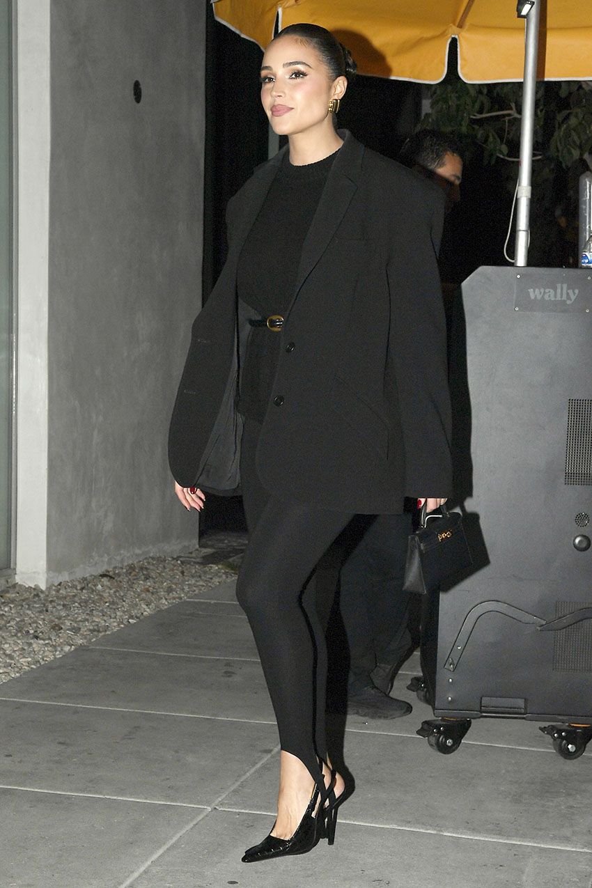 Olivia Culpo wearing a black blazer, black sweater, black stirrup leggings, black heels