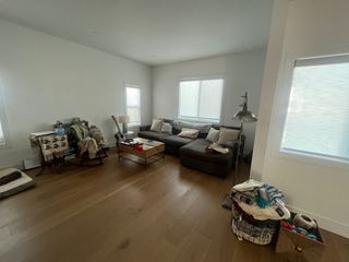 A cluttered living room with white walls and a corner sofa