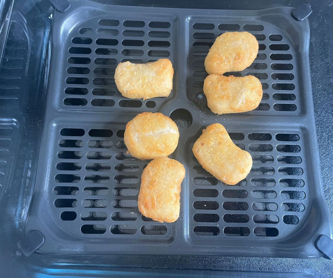 Six cooked nuggets on a black air dryer crisper tray