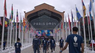 Basketball players walking towards a sign that says Paris 2024.