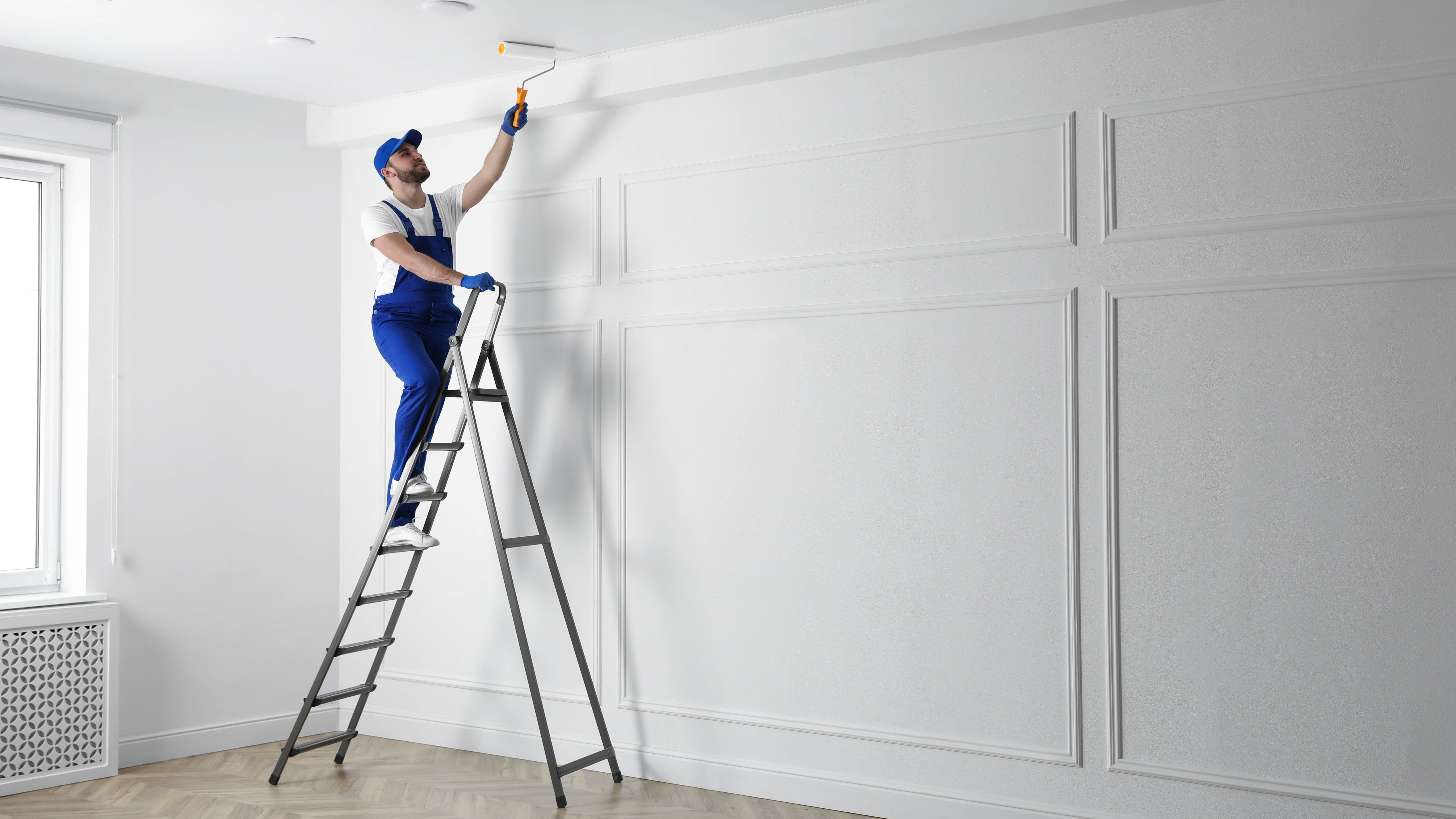 Un homme debout sur une échelle peignant le plafond avec un rouleau