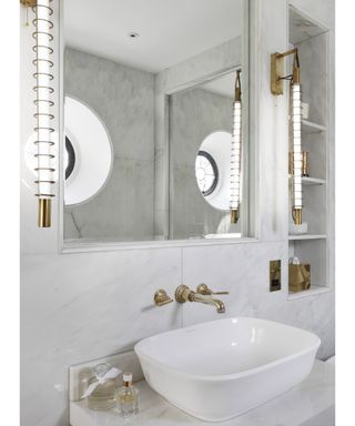White marble bathroom with built-in shelving by Victoria and Albert
