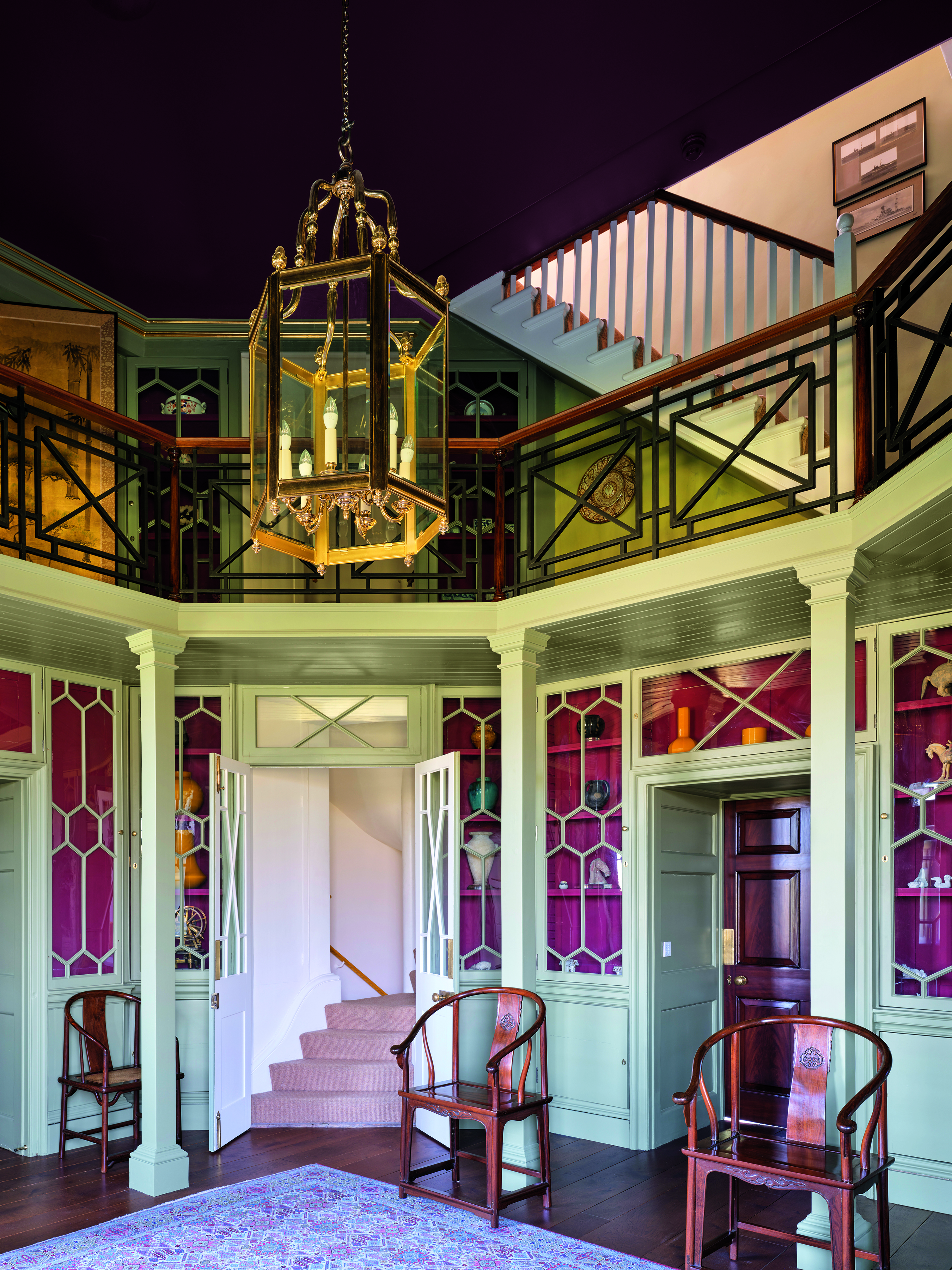 A beautiful old-fashioned hallway with teal walls, red detailing and a large ornate lampshade
