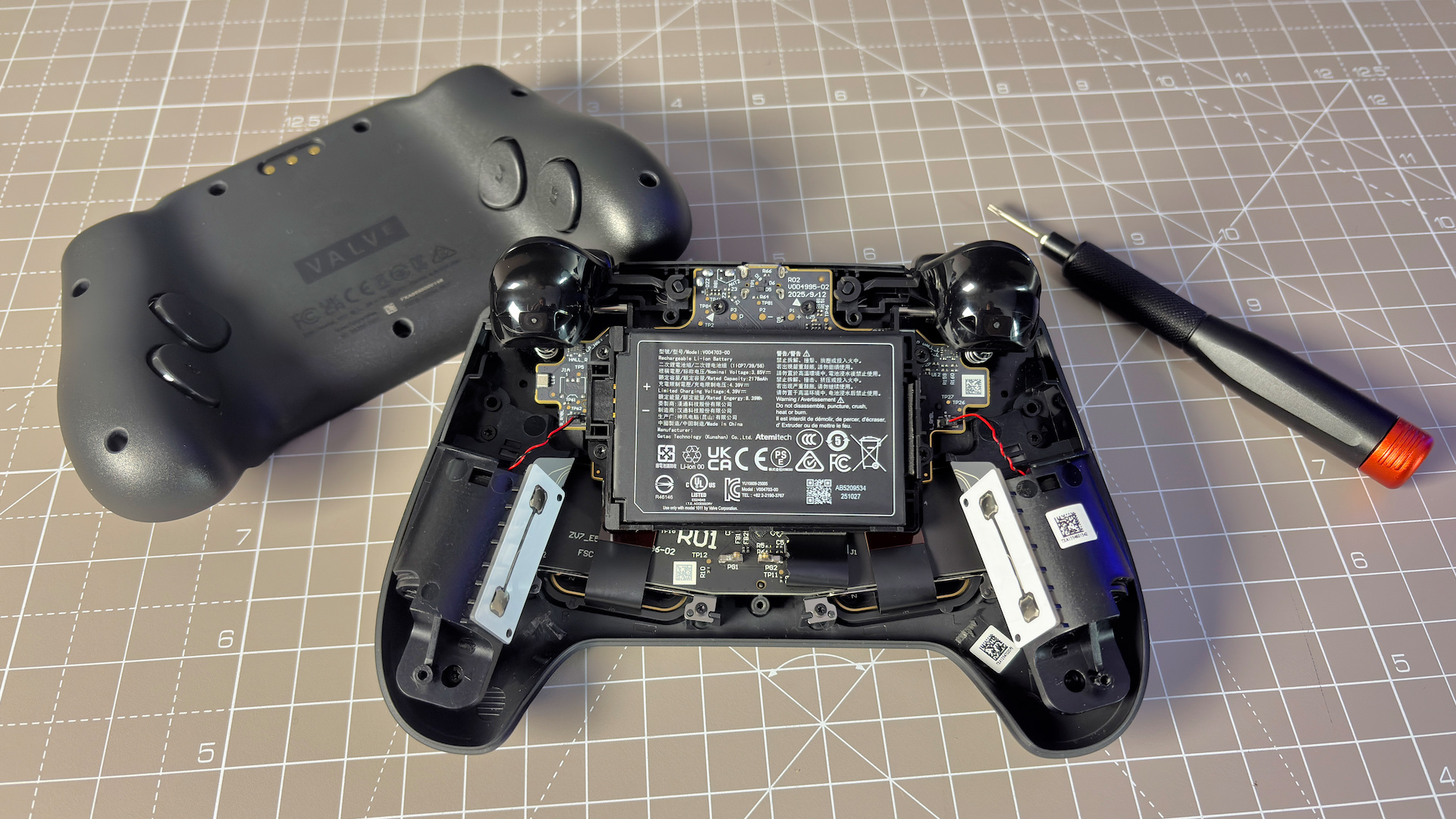 The Steam Controller on a desk during a teardown, with various parts removed.