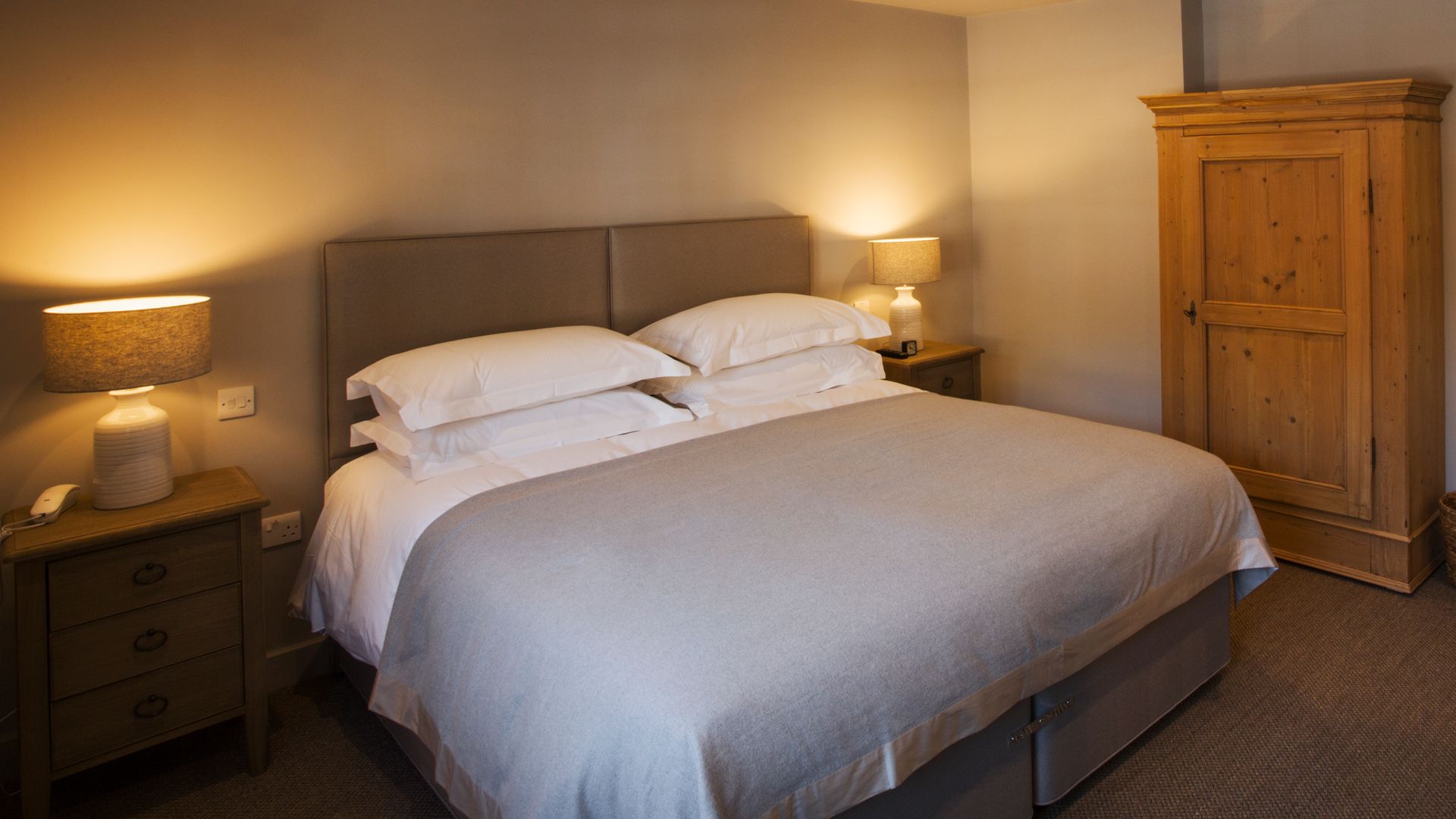 Cozy bedroom with ambient lamps on matching nightstands either side of the bed with empty wall space above the bed to follow how to arrange your bedroom using Feng Shui