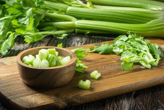 Celery stalks, chopped celery and celery leaves on a cutting board.