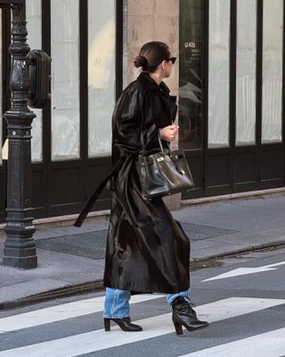 Hanna MW wearing a calf hair trench coat with a black Hermes Birkin bag, jeans, and black boots.