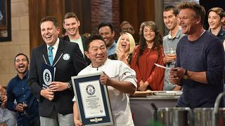 A group of people, including Gordon Ramsay and a Guinness World Records official, are smiling and laughing as a chef holds up a framed certificate.