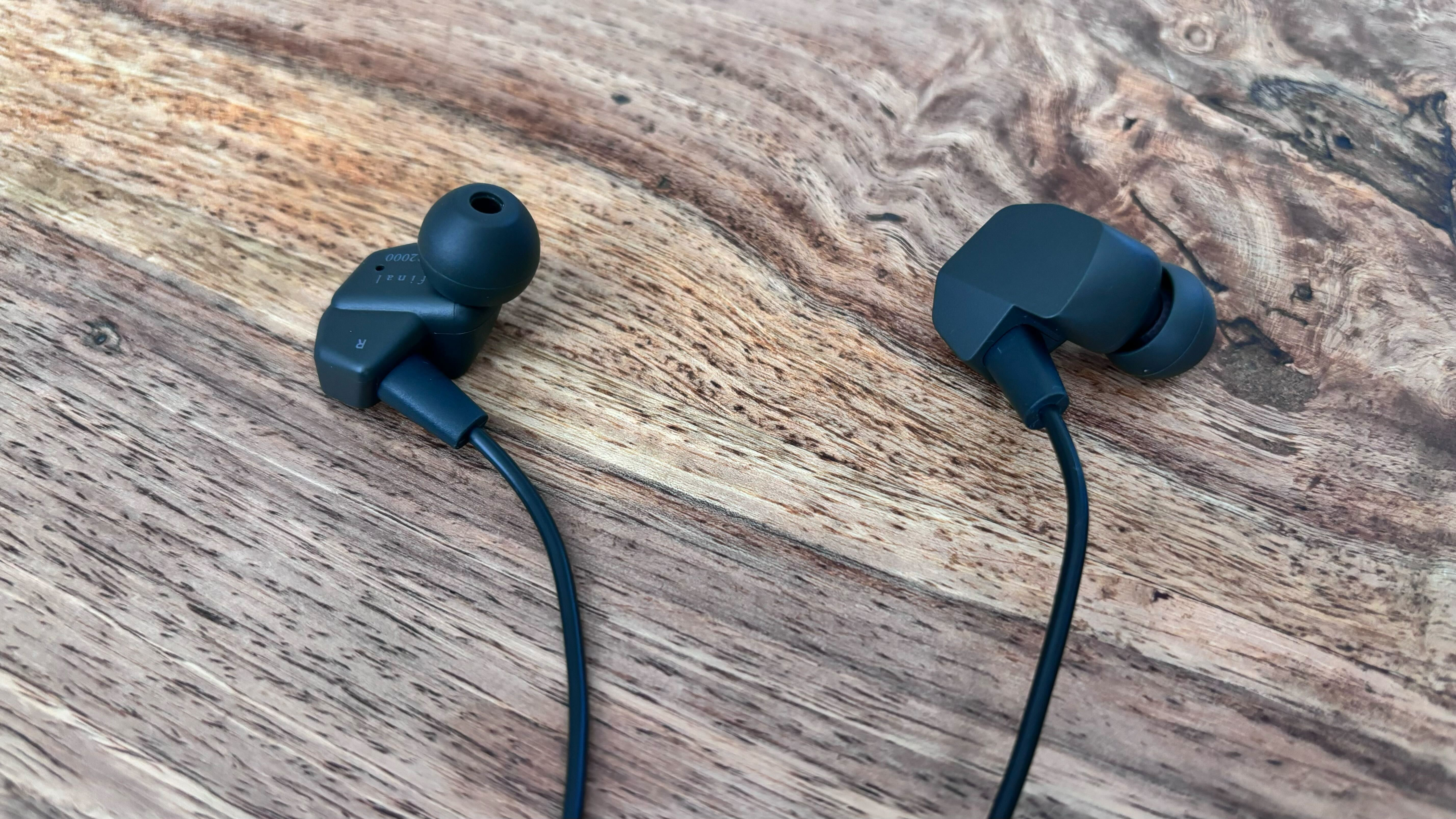 A close up shot of the Final VR2000 earbuds on a wooden surface.