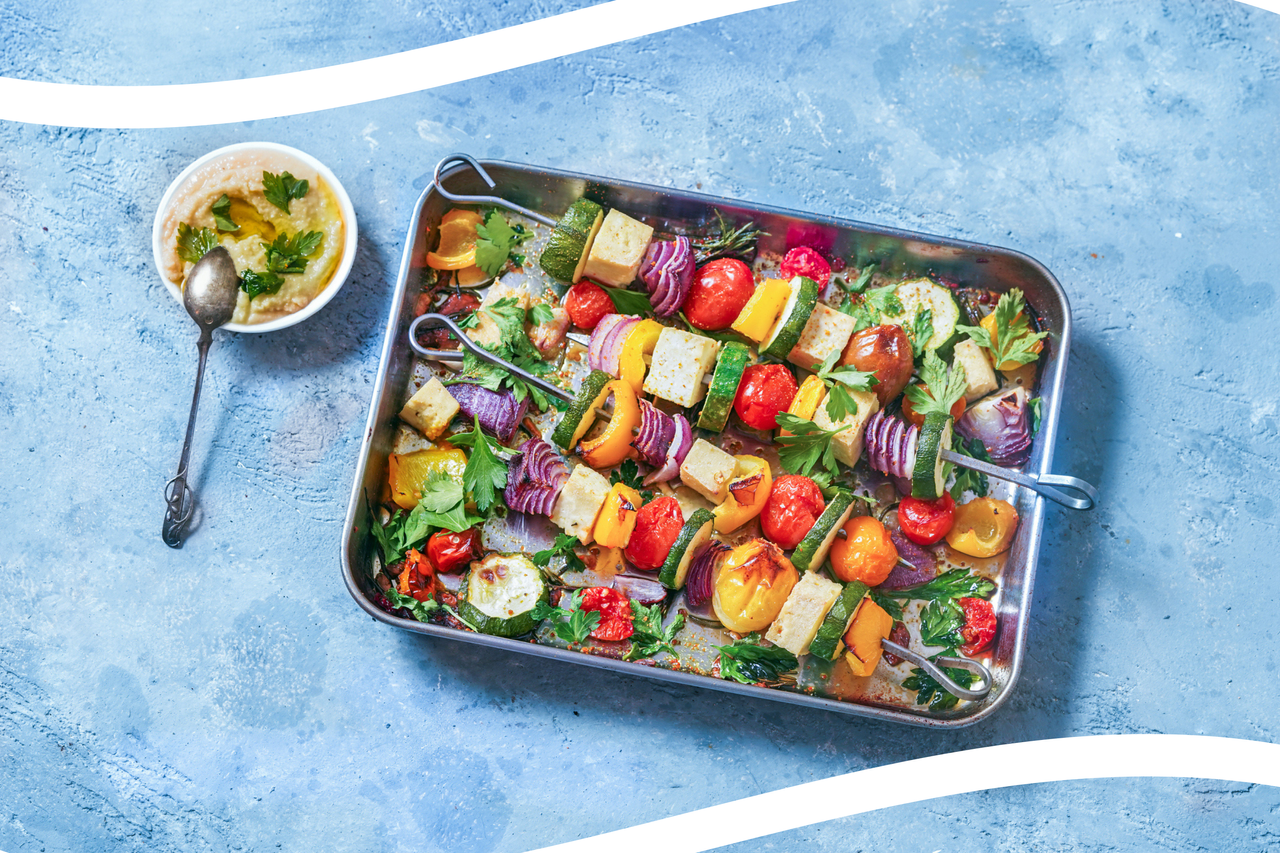 tray of roasted vegetables on a slate blue background with white lines across the top and bottom