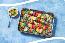 tray of roasted vegetables on a slate blue background with white lines across the top and bottom