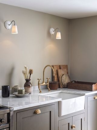 A kitchen with two wall scone lights and a ceramic sink