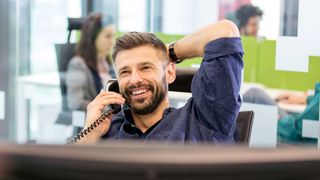 Man in office on a phone call, using one of the best business phone service.