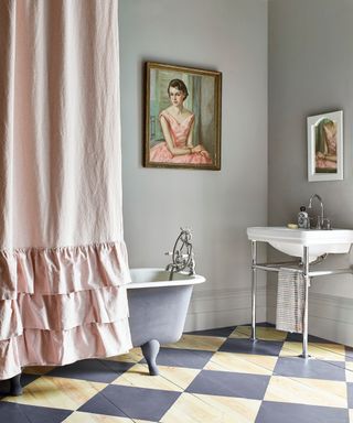 bathroom with freestanding bath, painted wooden and grey flooring, a freestanding basin with chrome rail and framed paintings of women on the walls