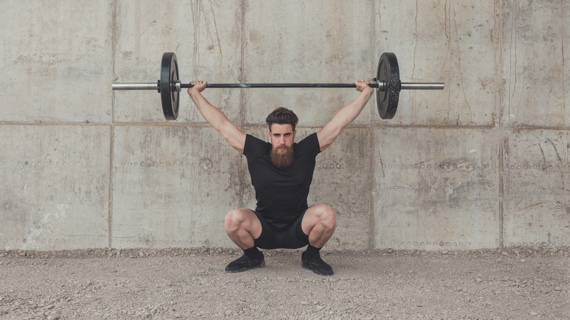 A man performing a barbell overhead squat
