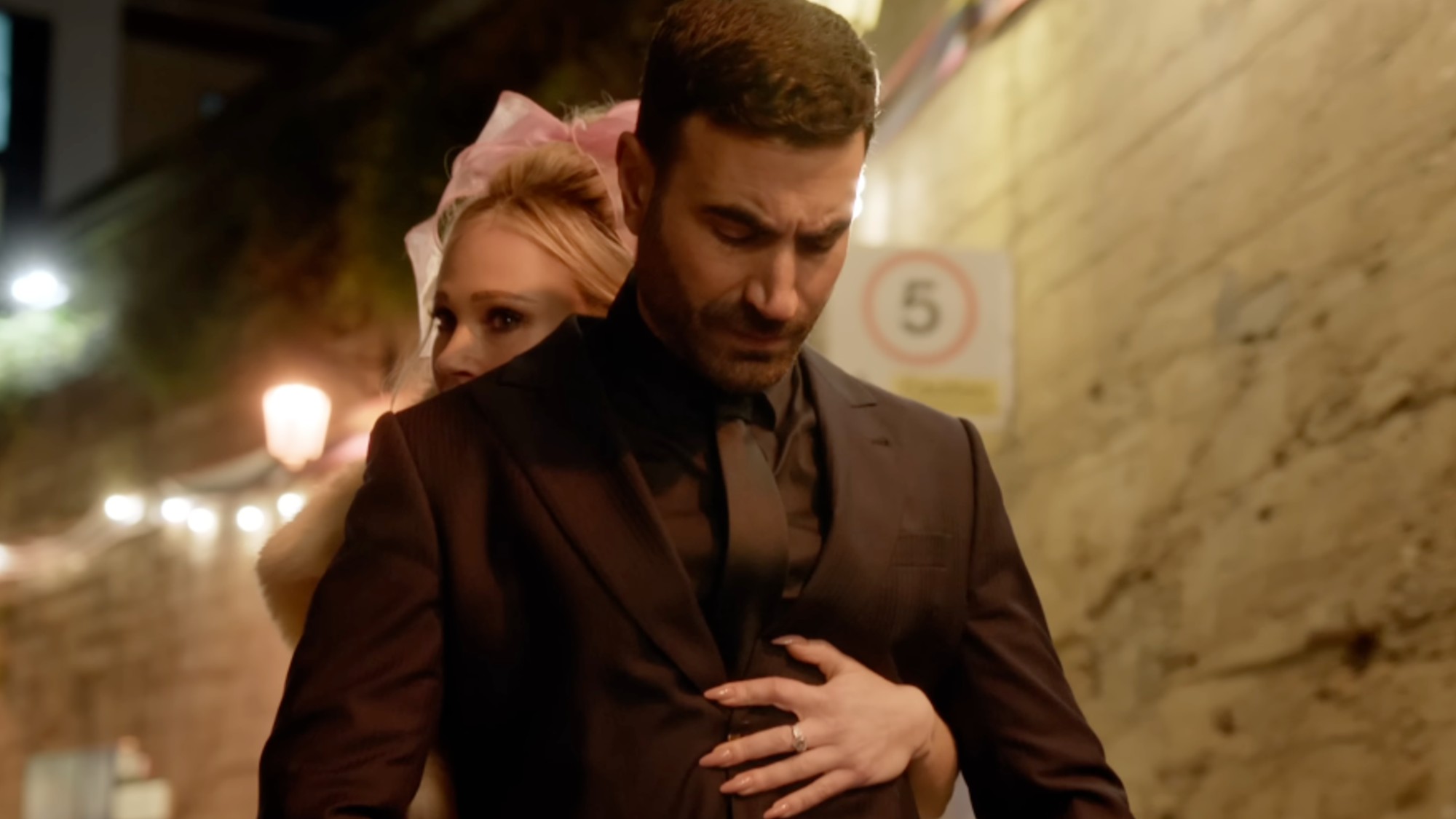 Juno Temple riding on a moped with Brett Goldstein, wrapping her arm around him, with Goldstein looking down at her hand