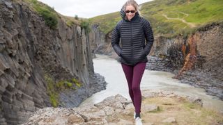 A woman hiking in Iceland with a waterfall behind her