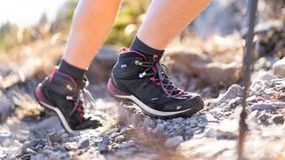 woman walking on a rocky trail wearing Quecha Women's Waterproof walking Boots MH500 MID