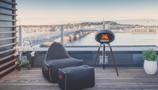 Freestanding firepit on a balcony overlooking water with a comfy lounge seat