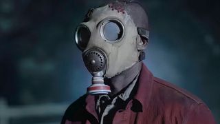 Creepy man in grey gas mask and maroon jacket in a scene from James Wan horror TV series Teacup season 1