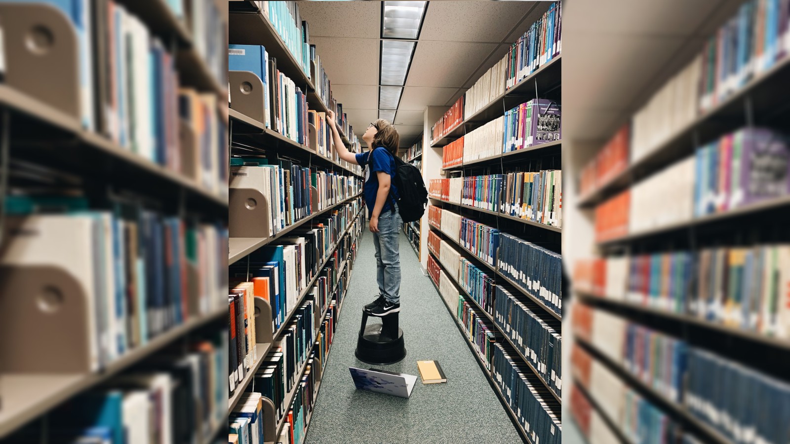 Elliott looking for physics textbooks on the top shelf.