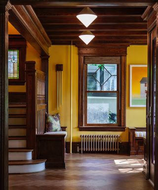 traditional hallway with wooden flooring, beams, yellow walls and column radiator