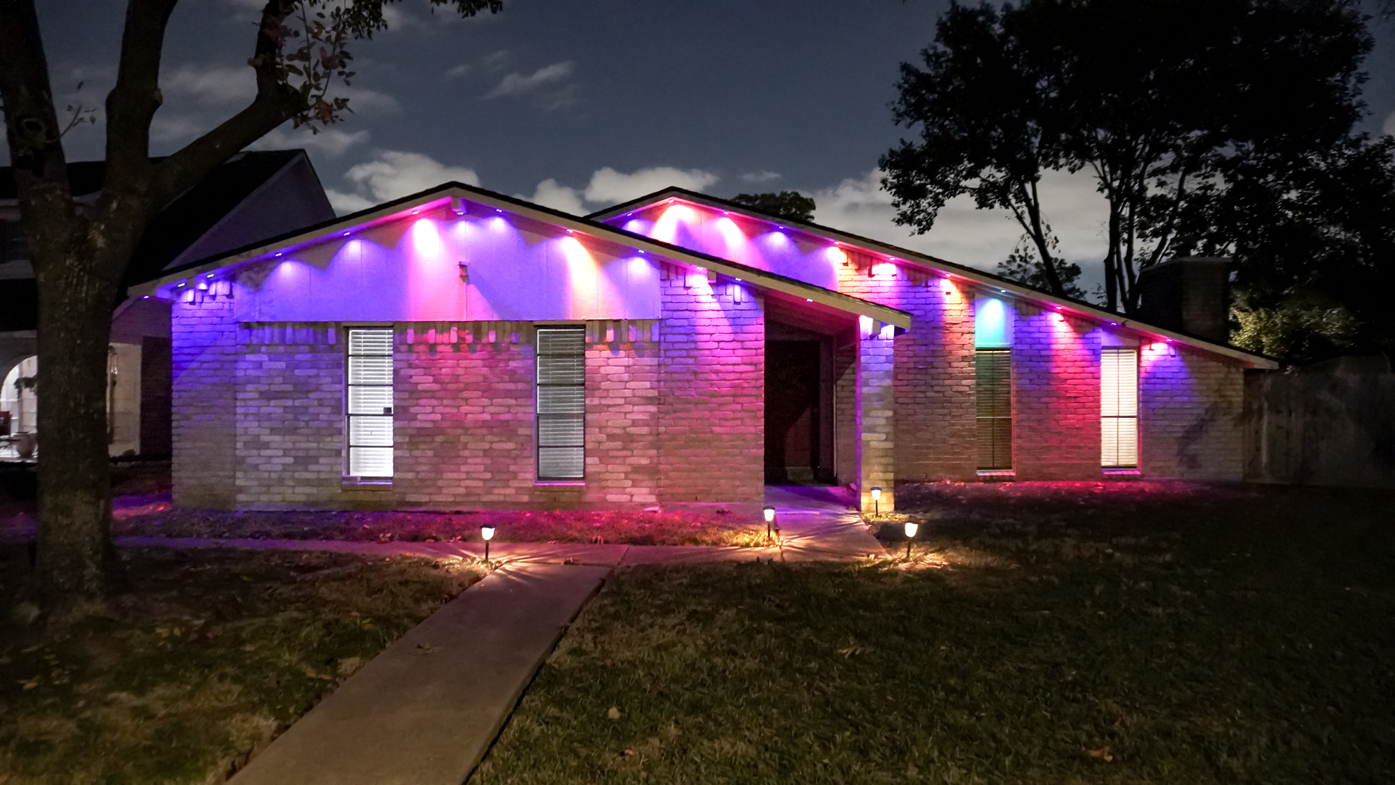 A house with Govee&#039;s Permanent Outdoor Lights Prism installed under its roof and set to a colored scene