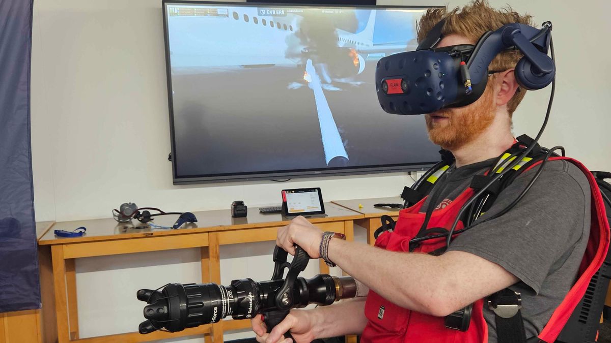 Ian Stokes with VR headset on with app footage behind them on a monitor.