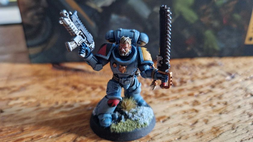 A Space Wolf model holding a gun and chainsword on a wooden table