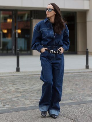 a photo of a woman wearing a T-shirt, denim button-down, wide-leg jeans, a studded belt, and ballet flats