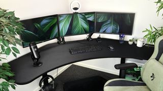 Arozzi Angelo gaming desk with three monitors on top, ring light, and plants 