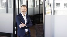 An older businessman stands outside the office.