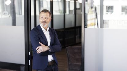 An older businessman stands outside the office.