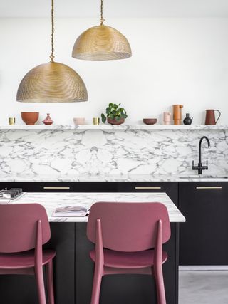 marble kitchen with gold pendants, two pink bar stools, marble shelf