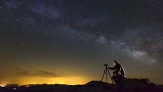 DSLR vs mirrorless for astrophotography - a man takes a photo of the night sky