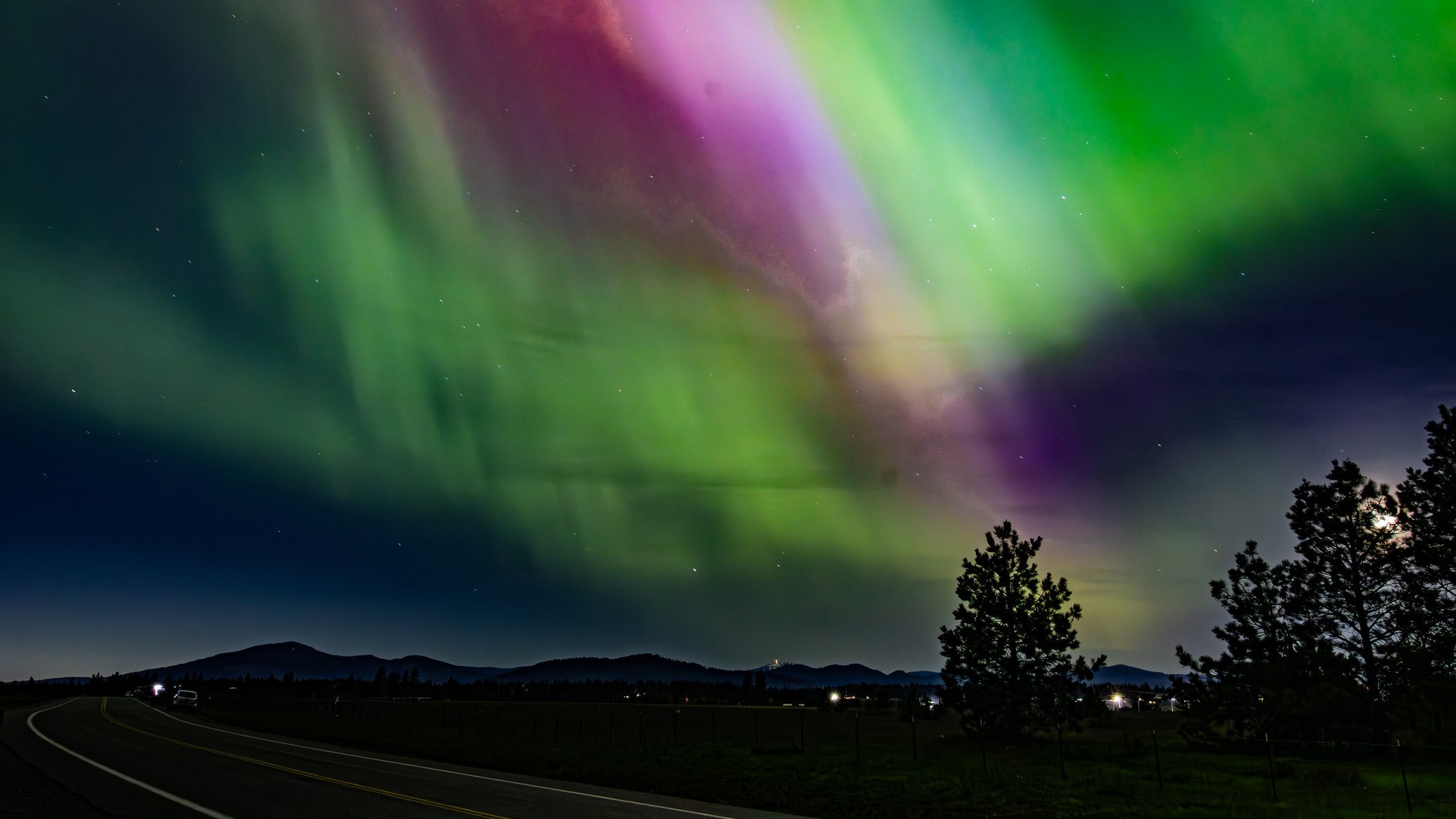 Northern lights from Idaho appear as huge curtains for green and magenta light shining in the night sky. 