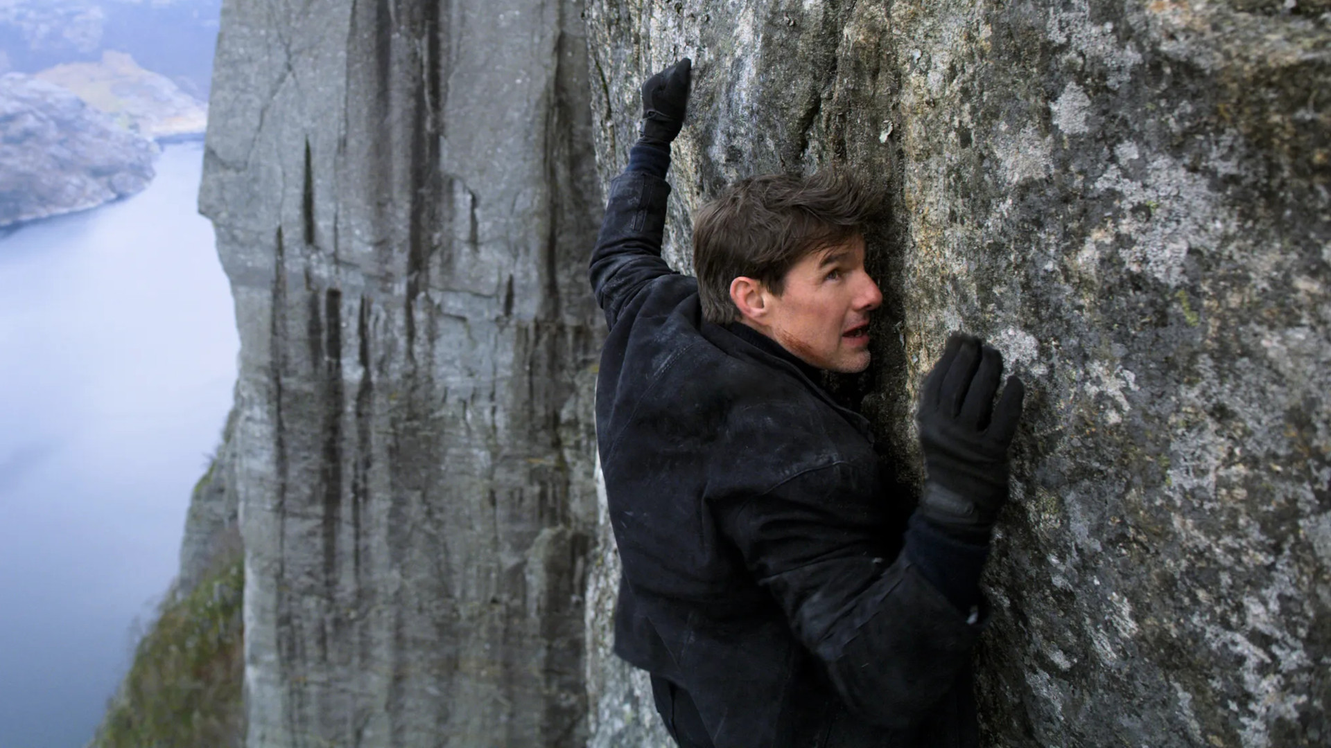 Mission Impossible movies in order: Tom Cruise as Ethan Hunt climbing a mountain.