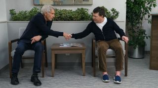 Michael J. Fox shaking hands with Harrison Ford while seated in doctor's waiting room in Shrinking