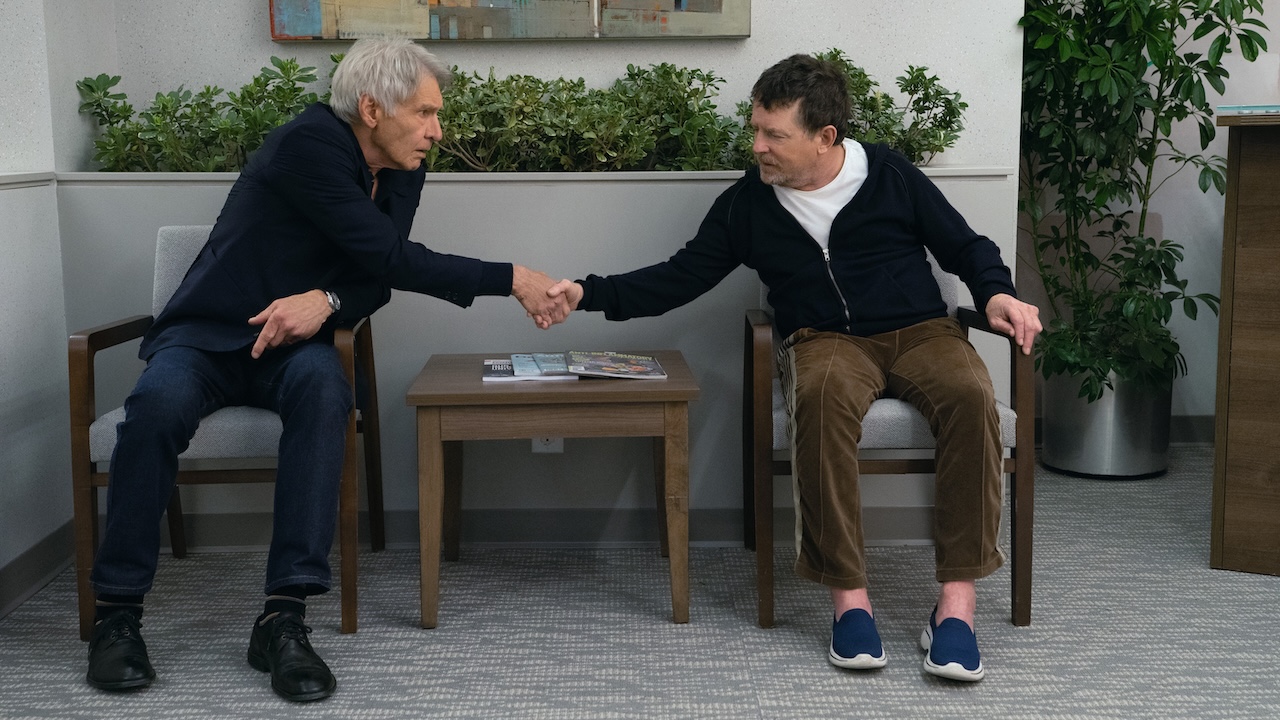 Michael J. Fox shaking hands with Harrison Ford while seated in doctor's waiting room in Shrinking