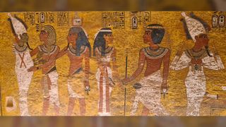 This is a picture that shows the interior of King Tutankhamun's tomb and wall paintings in the tomb of Tutankhamun in Egypt. The background is gold and there are six people in total, each wearing elaborate headdresses and neck pieces.
