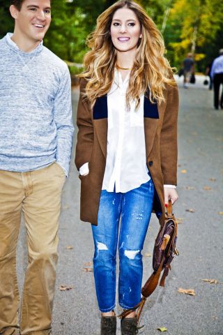 Woman in a brown coat, white shirt and blue jeans.