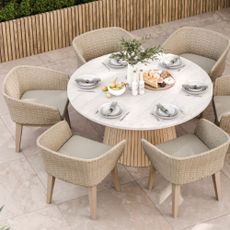 Photo of dining chairs and marble table on marble floor in garden
