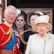 Queen Elizabeth standing between King Charles and Andrew Mountbatten-Windsor, both in red uniforms