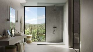 modern bathroom with smooth stone walls and floor, walk in shower with glass screen, large countertop with sinks and picture window looking over forest
