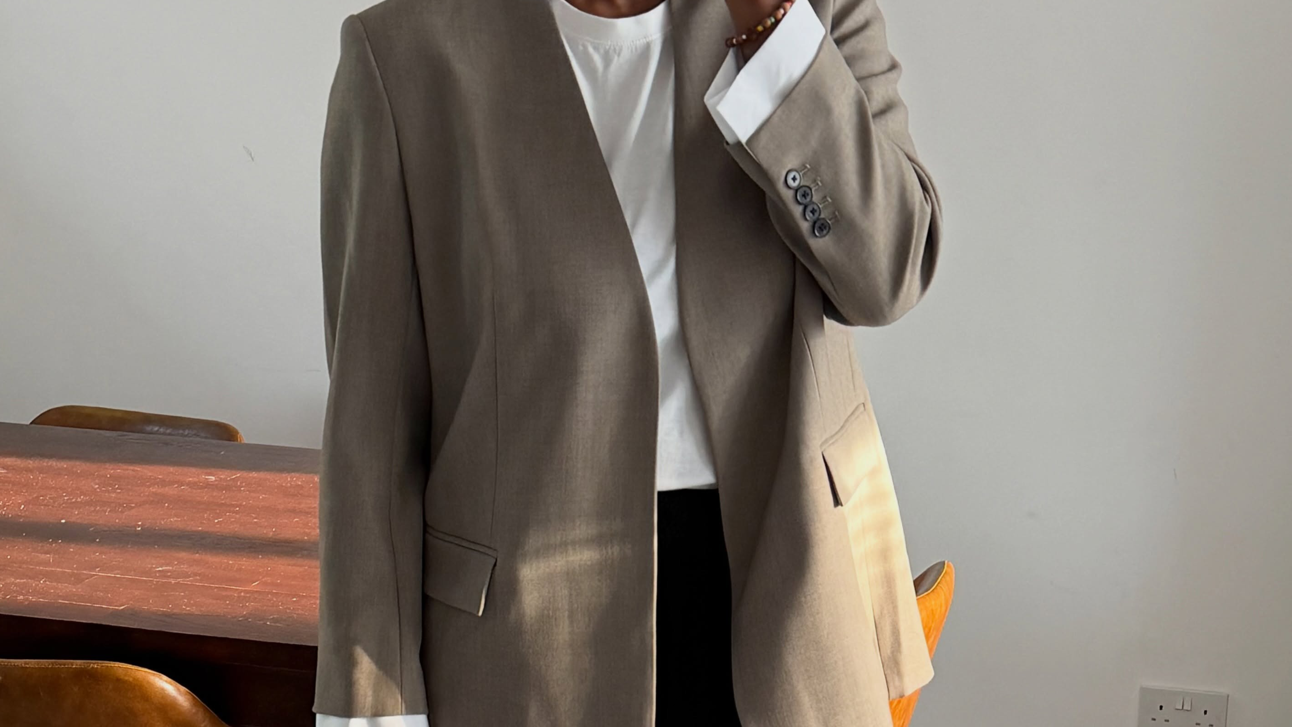 Woman wearing black leggings with white t-shirt, blazer, and black bag.