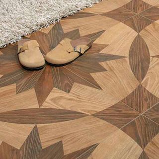 Estrellar Wood Effect Tiles with star and circular patters, and brown slippes on the tiles next to a rug