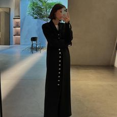 Laura wears a long black coat.