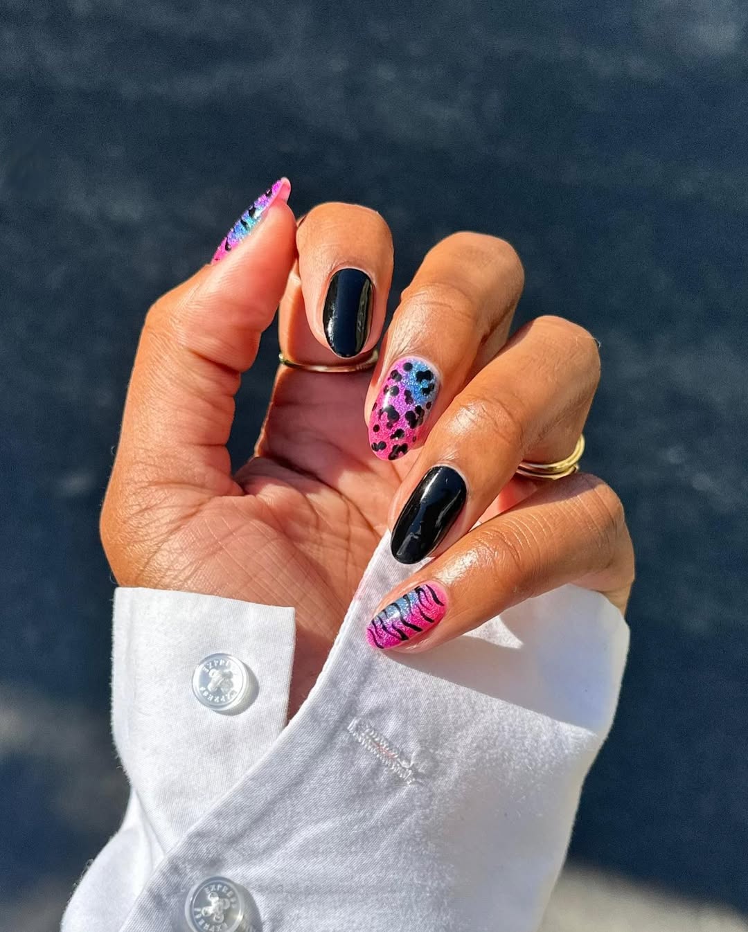 leopard nails in pink and blue with a shiny black accent nail