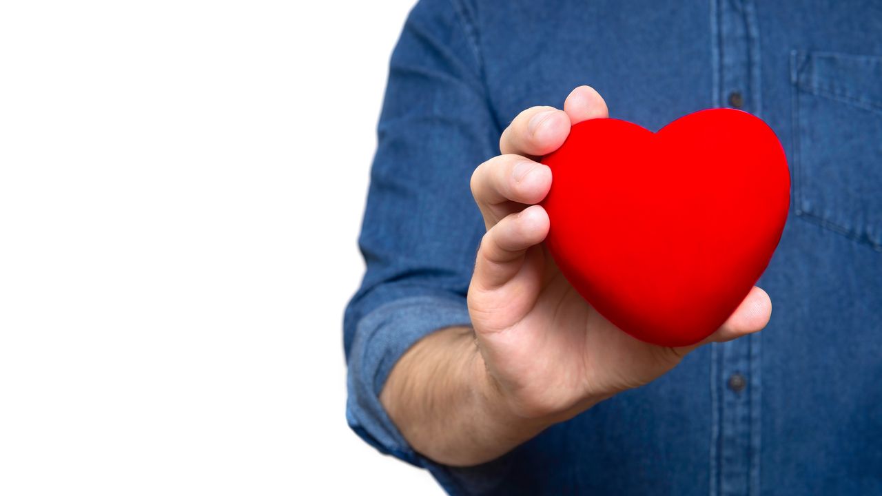 A man holds a heart knickknack.