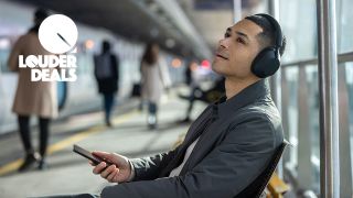 Man listening to music at a train station wearing Sony WH-1000XM5 headphones